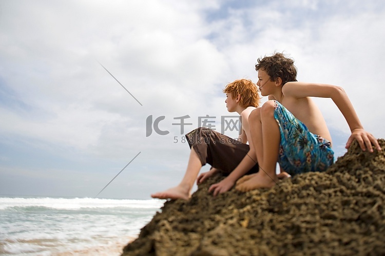 两个十几岁的男孩坐在海边看风景