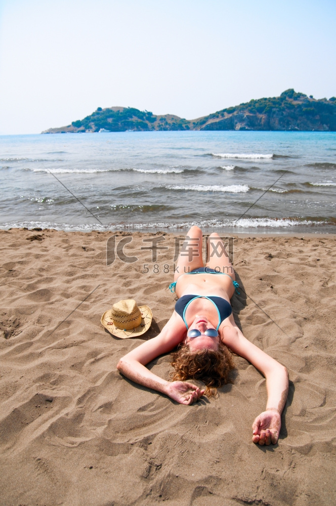性感的女人躺在海滩上，俯瞰