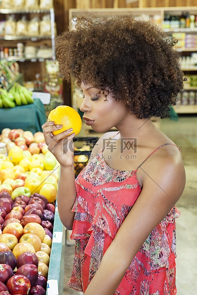 非裔美国女性在超市闻着新鲜橙子