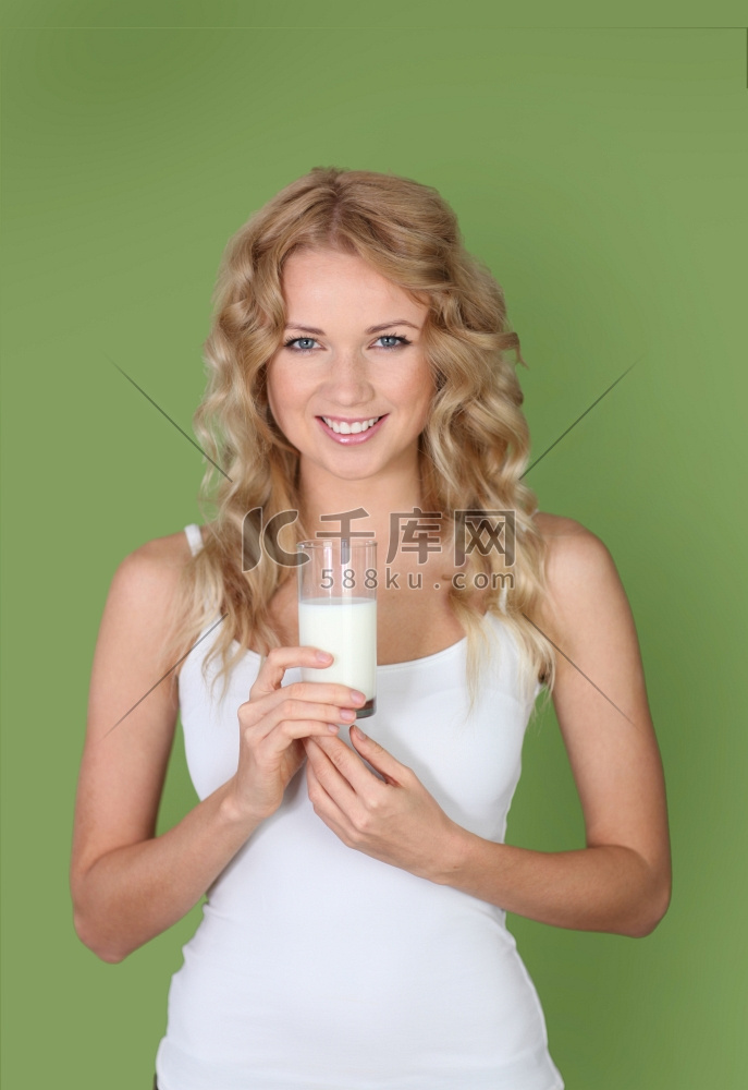 绿色背景上拿着一杯牛奶的妇女肖