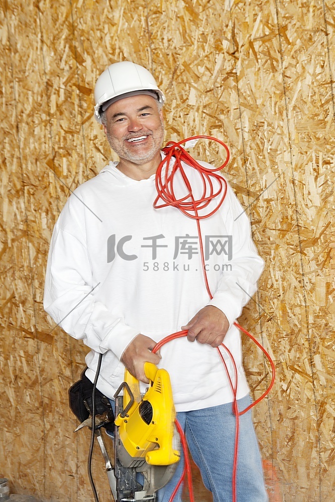 快乐的男性建筑工人手持电锯和红