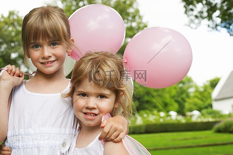 花园里拿着派对气球的两个女孩