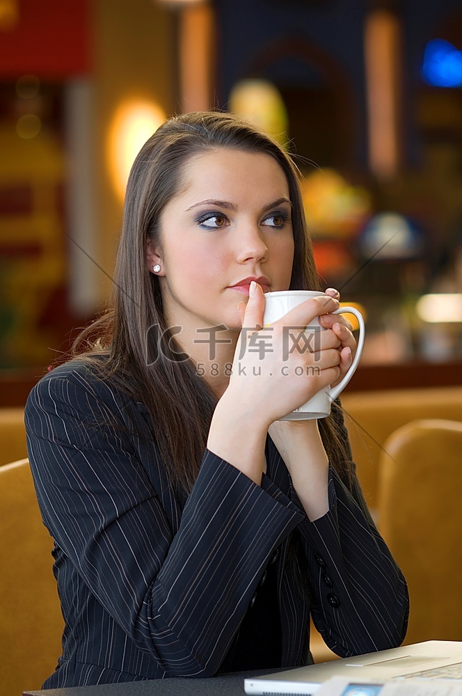 年轻女子双手捧着一杯热茶取暖