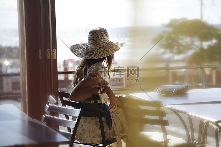 戴着太阳帽的女人坐在交通咖啡馆