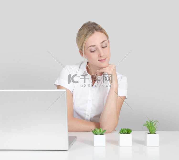 金发女郎坐在计算机和绿色植物