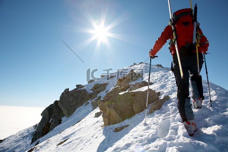 男子滑雪攀登者攀登积雪的山脊；