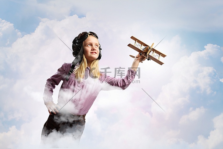 戴着飞行员头盔的小女孩在云的背
