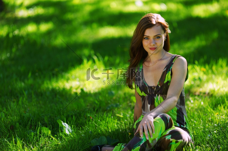坐在绿色草地上的黑发女郎