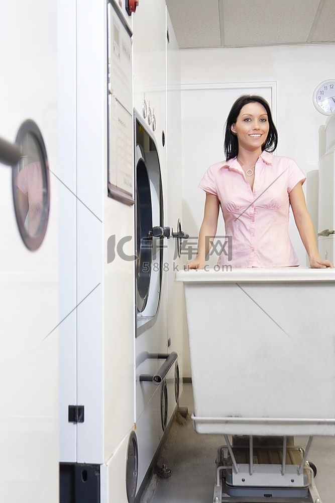 一位快乐的中年妇女在洗衣房推着