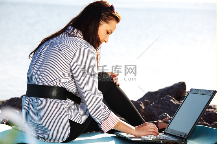 有笔记本电脑出海背景的女性