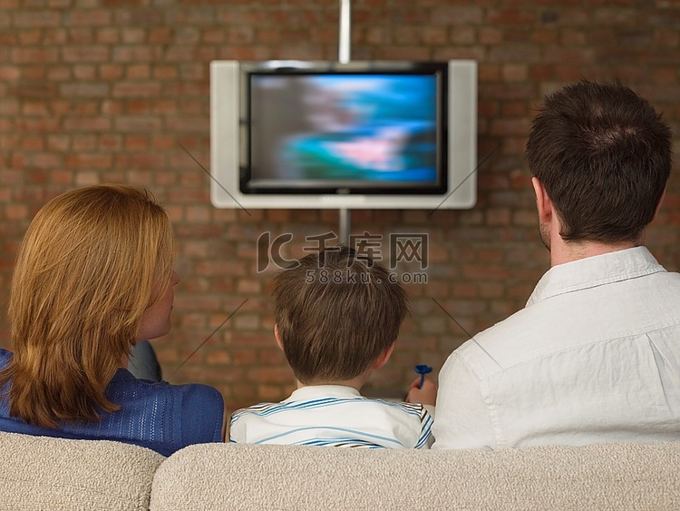 父母之间的男孩看电视