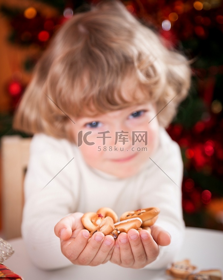 快乐的孩子拿着饼干在圣诞彩灯的