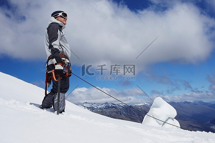 带着安全线站在雪坡上的登山者