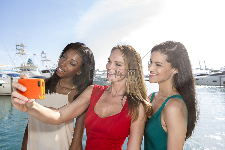 采取与智能手机拍照的三个女人的