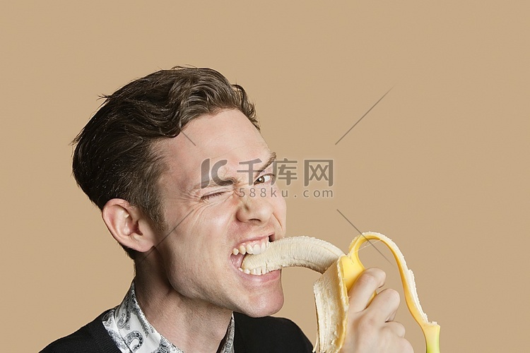 一名中年男子在彩色背景下咬香蕉