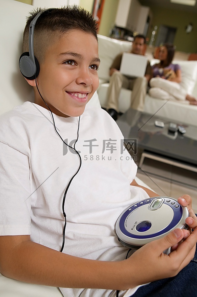 男孩在便携式CD播放机上听音乐