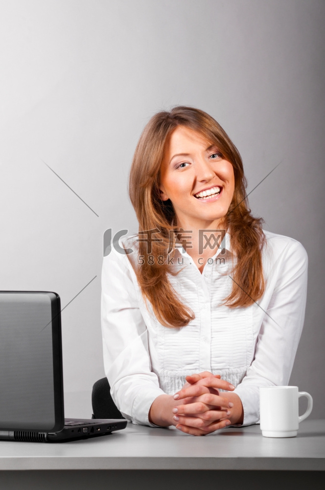 女商人拿着笔记本电脑坐在办公室