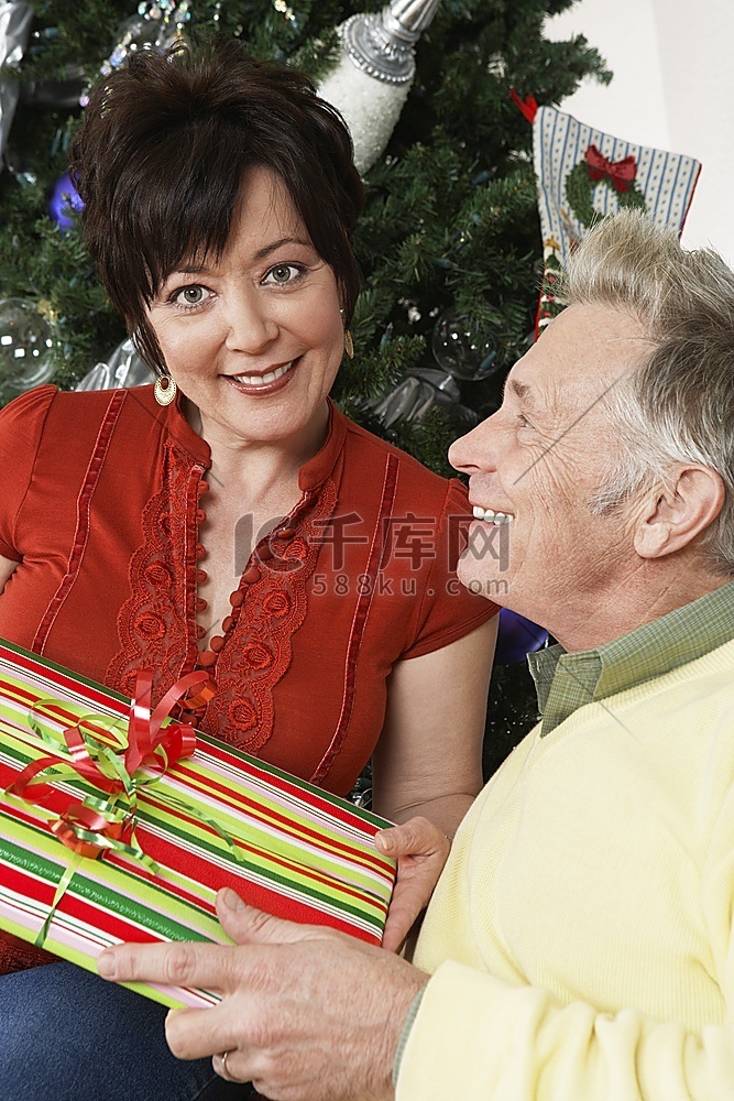 高年级夫妇在圣诞树前拿着礼物