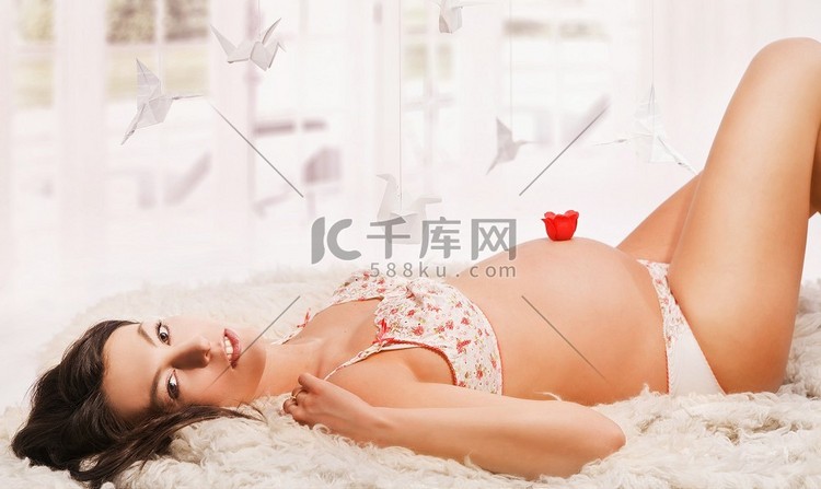 年轻怀孕美女的肖像，躺在地毯上