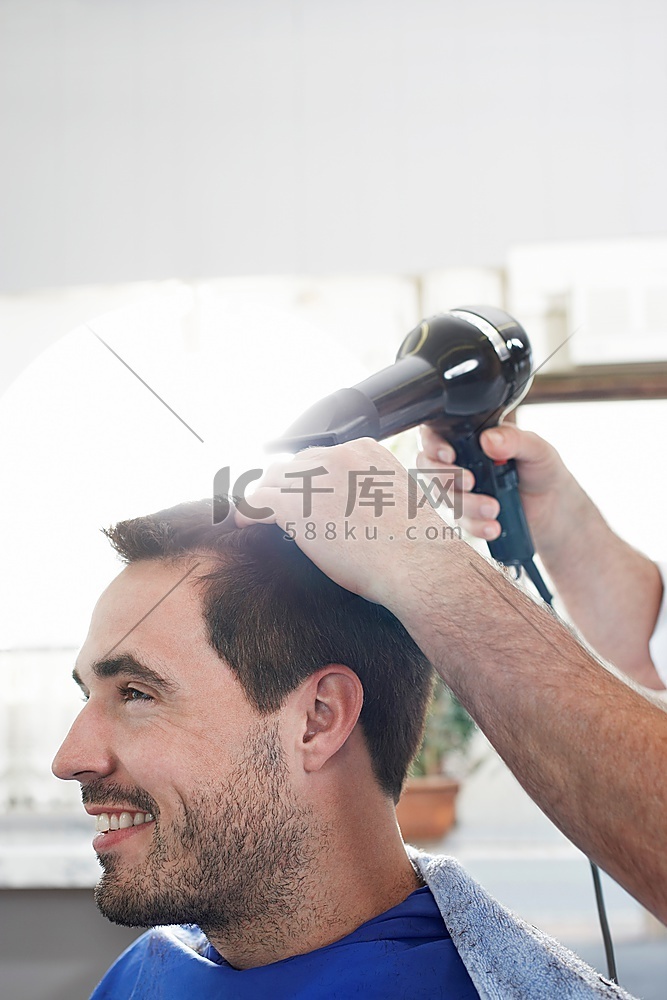 理发师在理发店烘干男人的头发