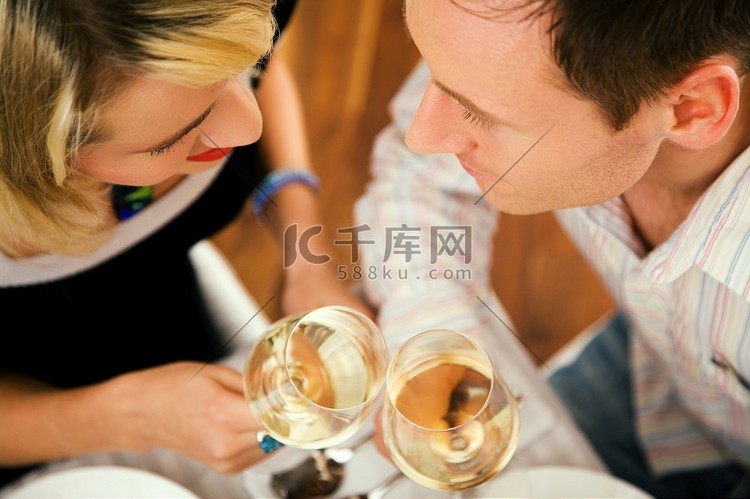 年轻情侣浪漫晚餐：碰杯；聚焦人