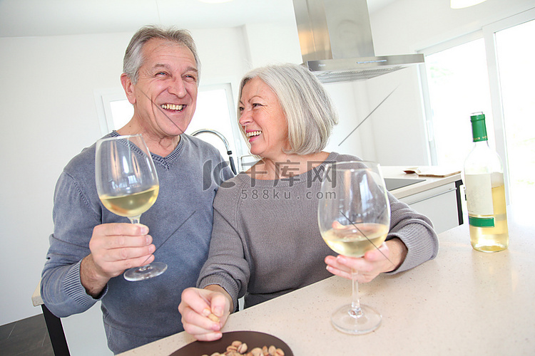 喝葡萄酒的高级夫妇在家庭厨房