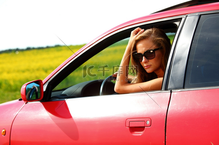 女人在红色的汽车得到了窗口