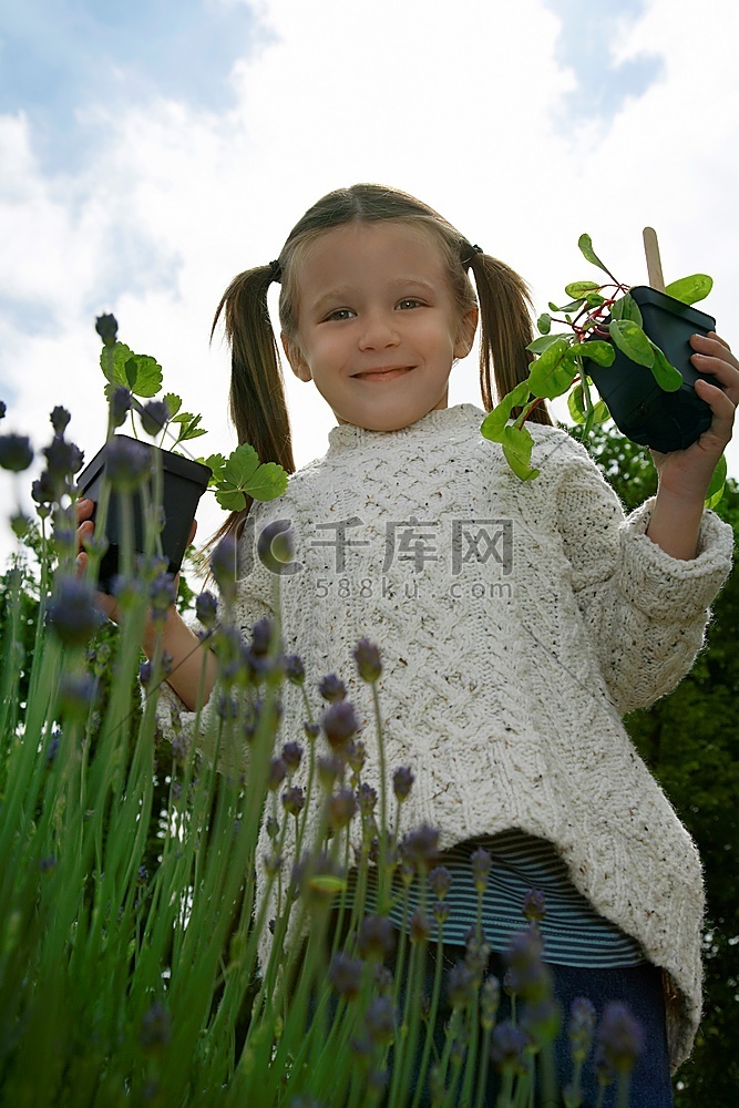 女孩(5-6岁)在花园里拿着植