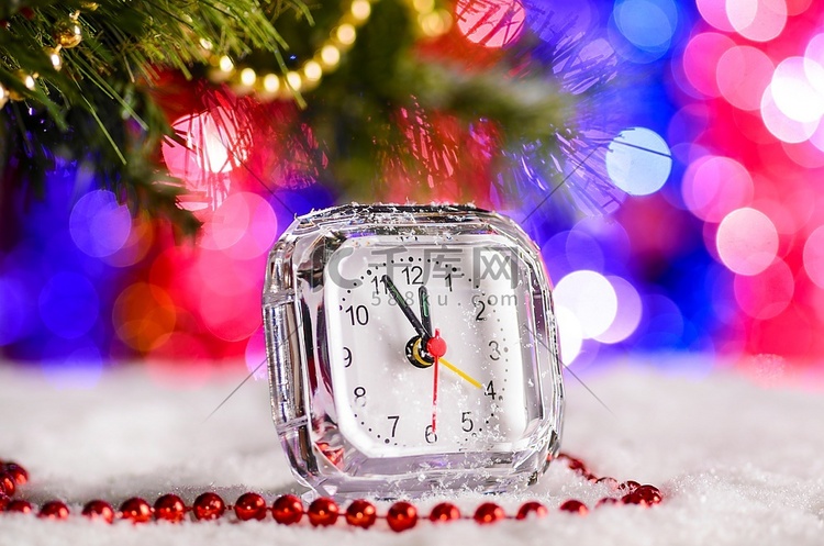 圣诞树下雪地上的礼品盒和钟表
