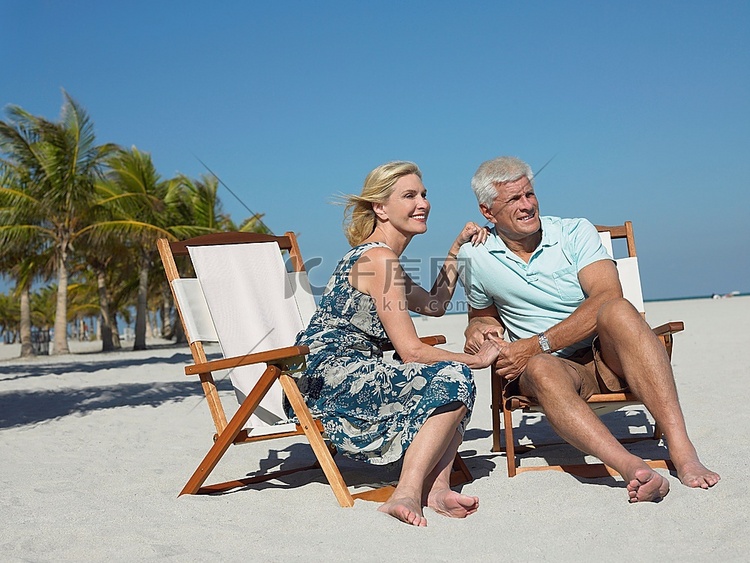 一对老年夫妇坐在热带海滩的日光