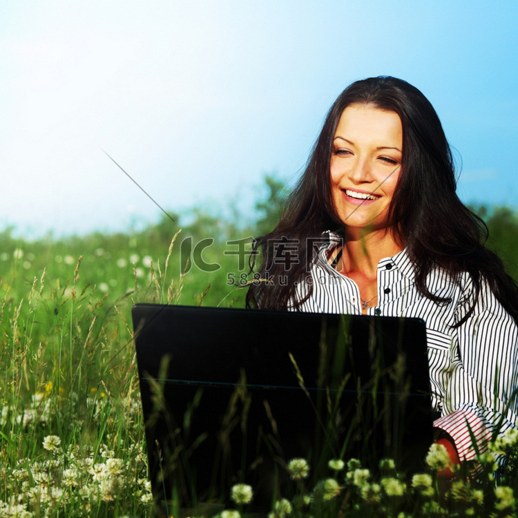 有笔记本电脑的女孩在绿草上