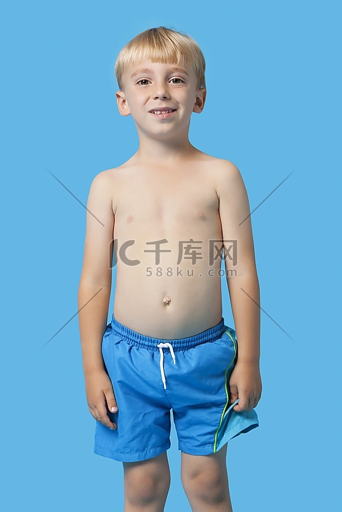 蓝色背景上穿着泳裤的快乐小男孩