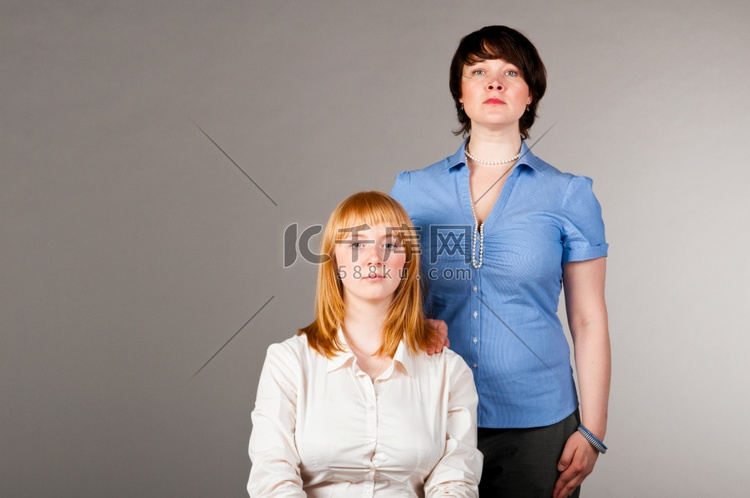 两个女商人，一个坐在椅子上，另
