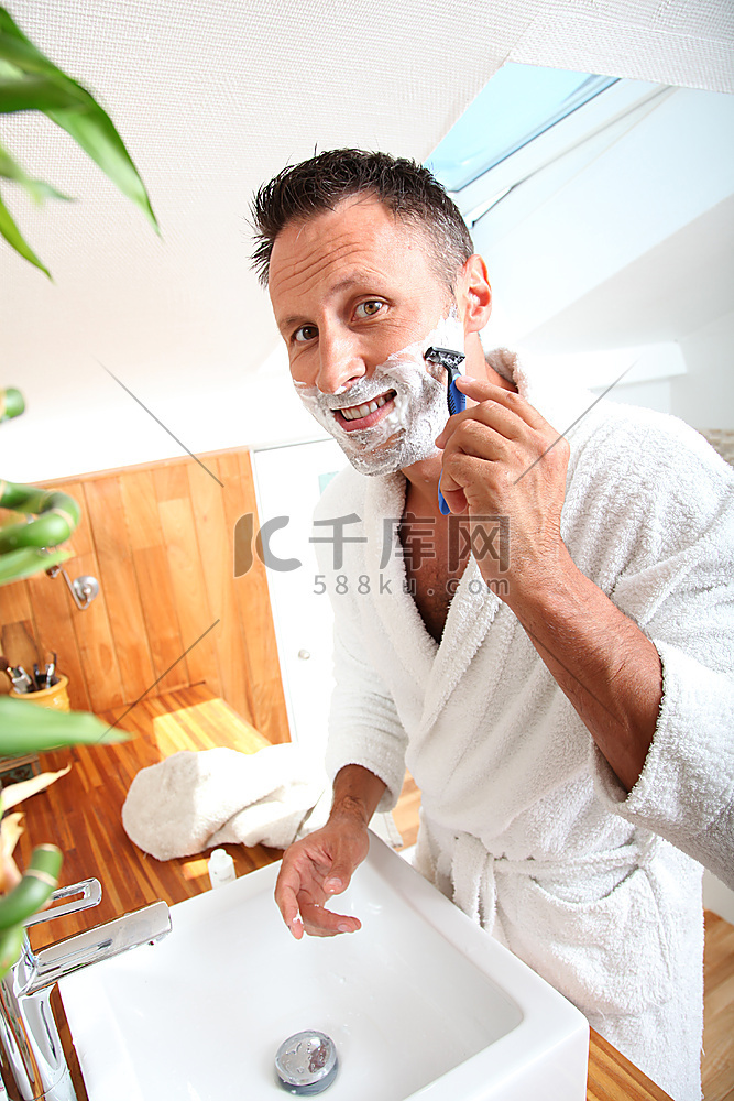 英俊的人刮胡子在浴室