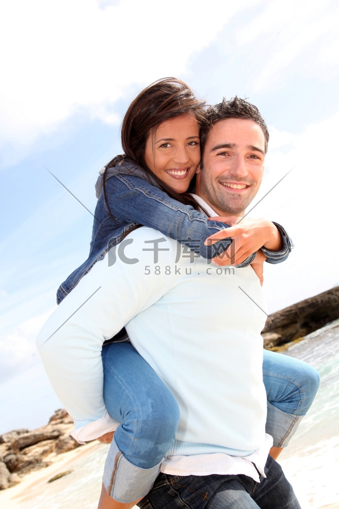 一名男子在海滩上背着女友搭车