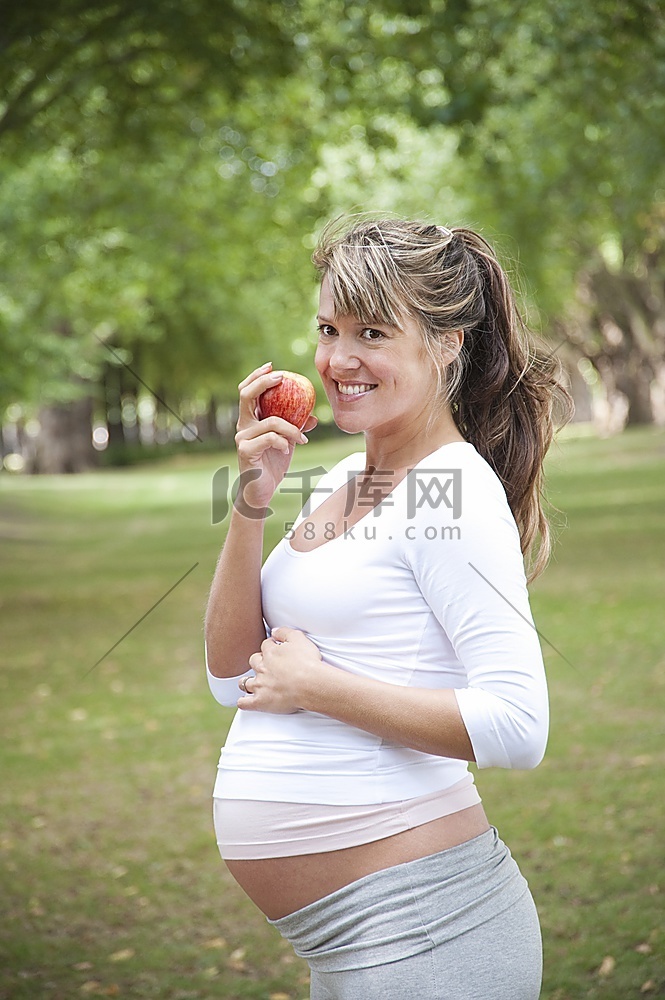 一名孕妇在公园里吃苹果