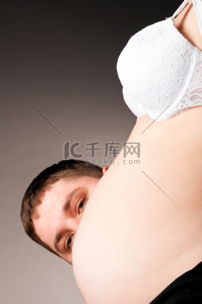 一名男子在他怀孕的妻子的肚子后