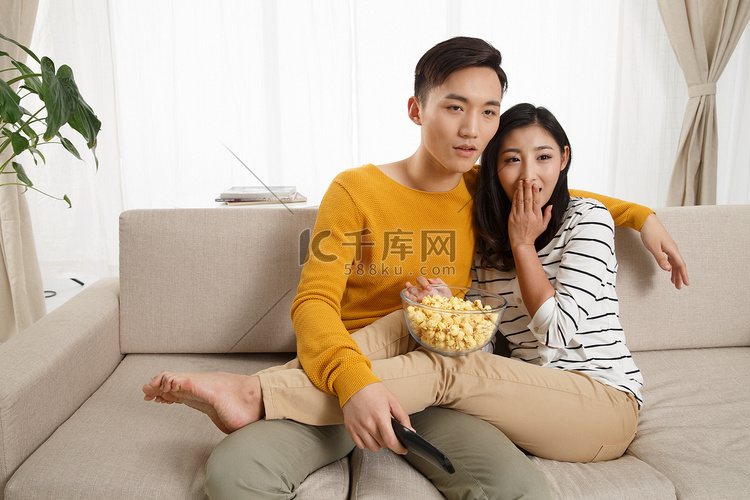 青年情侣坐着沙发上看电视
