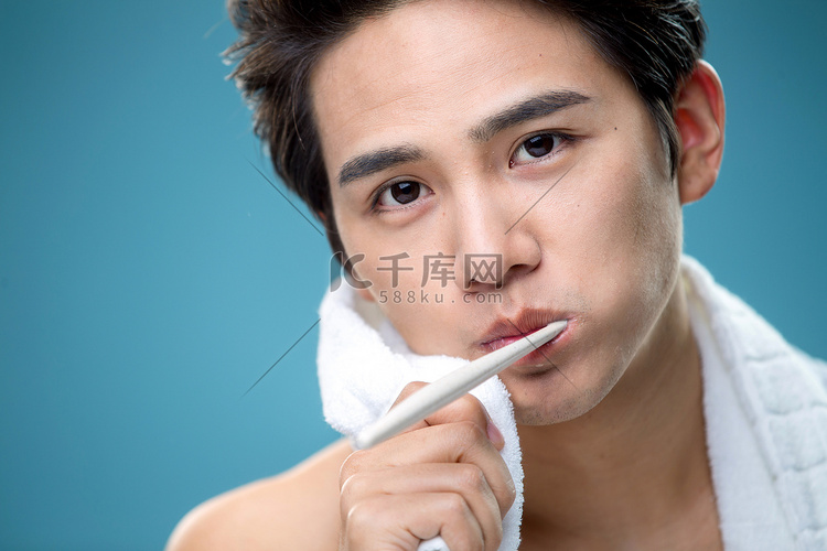 年轻男人用毛巾擦刷牙时脸上的泡