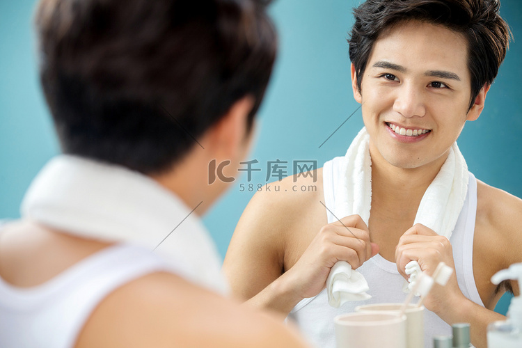 快乐的年轻男人拿着毛巾照镜子