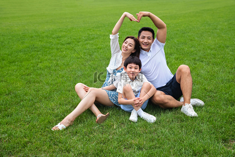 幸福的三口之家坐在草地上