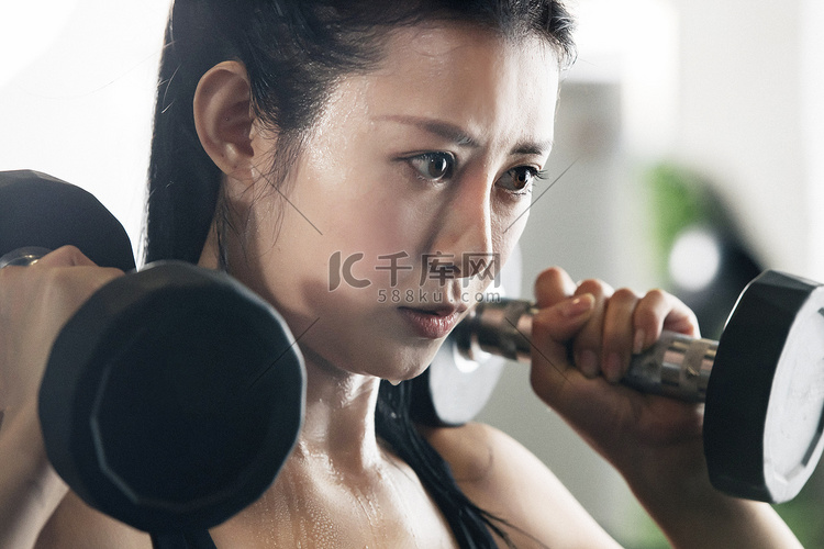 年轻女子在健身房练习举哑铃