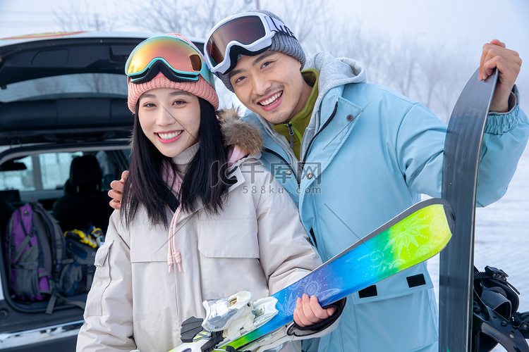 快乐的青年伴侣拿着滑雪板站z在