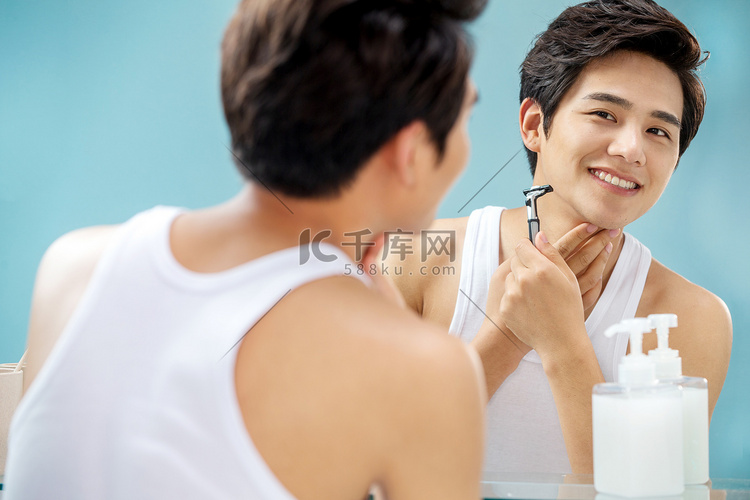 青年男人对着镜子刮胡子