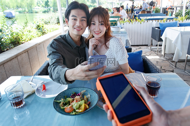 年轻情侣在餐厅用手机付款