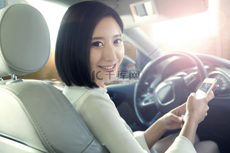 青年女人坐在汽车里看手机