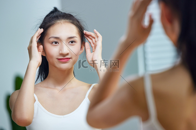 漂亮的年轻女人照着镜子梳头发