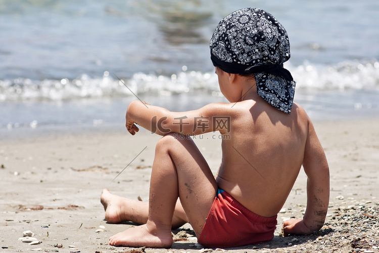 坐在沙滩上的小男孩