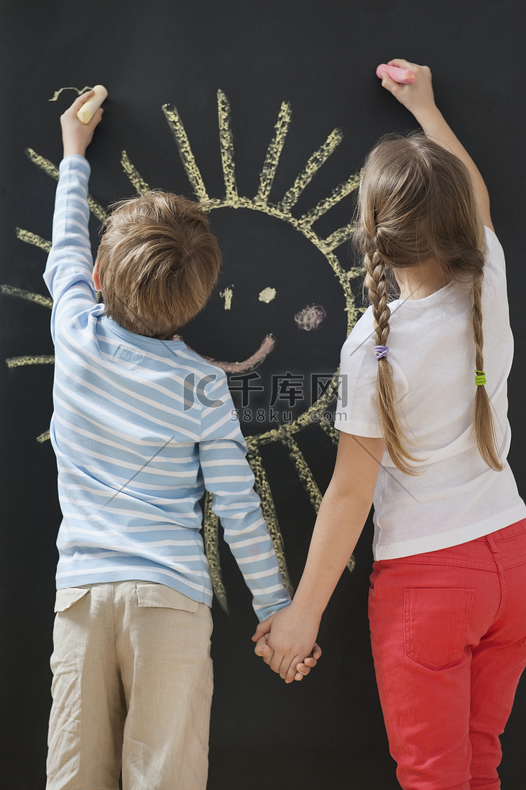 手牵着手在黑板上画太阳的兄弟姐
