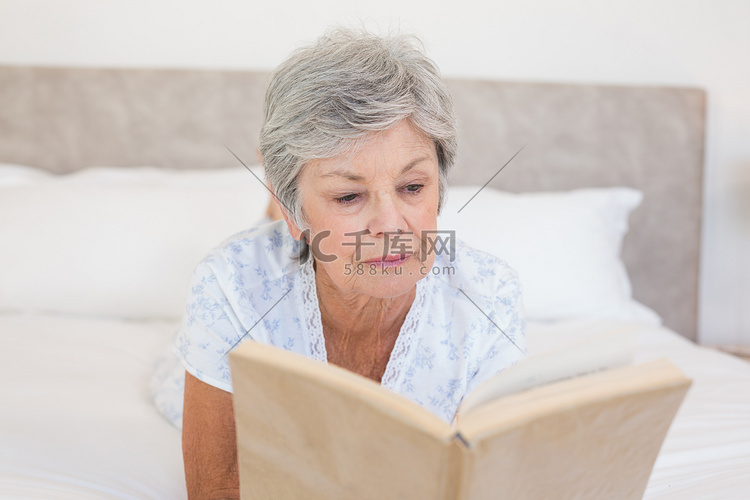 老年妇女在床上看故事书